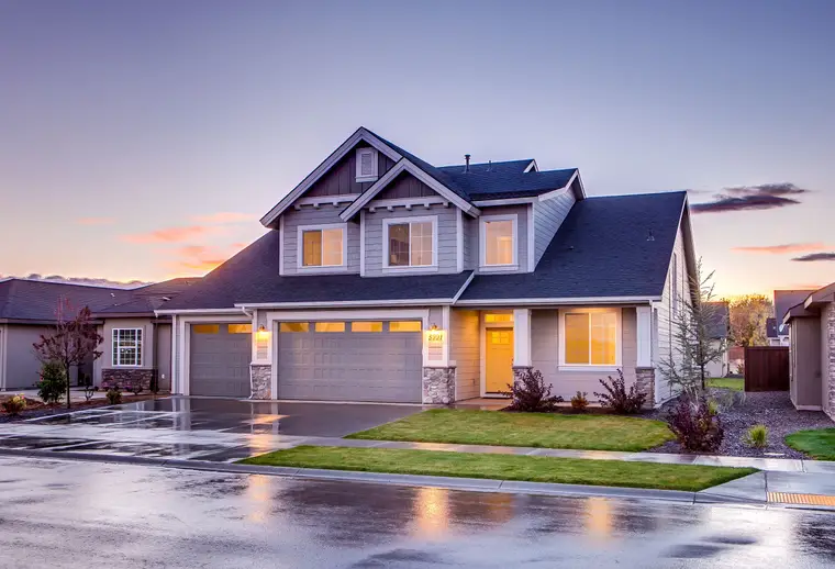 Two-story home with lights on at sunset