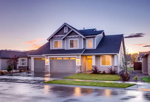 Two-story home with lights on at sunset