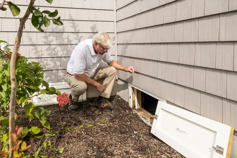 Inspector checking a crawl space at the side of a house